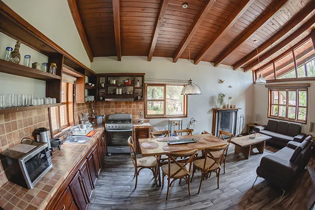 Interior de cabaña con cocina, comedor y sala.